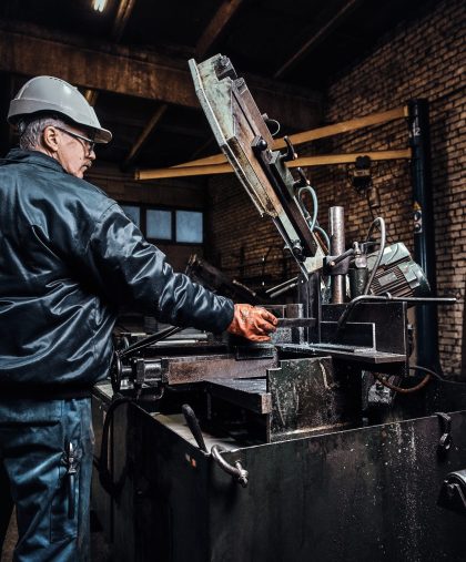 Experienced worker is working at metal factory using special machine tool KENITRA I2MK.