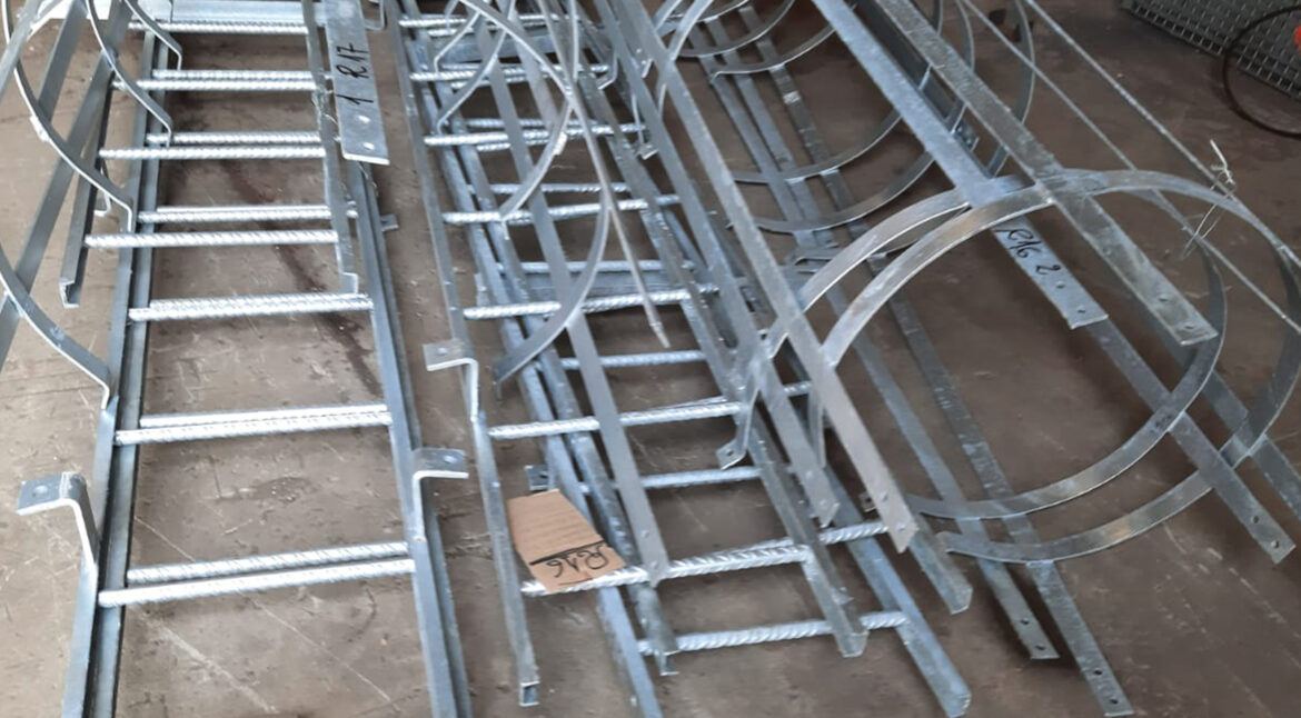 Portrait of factory worker in protective equipment holding thumbs up in production hall.
