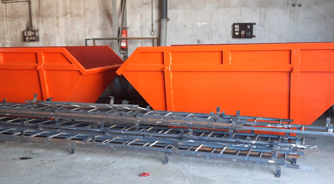 Portrait of factory worker in protective equipment holding thumbs up in production hall.
