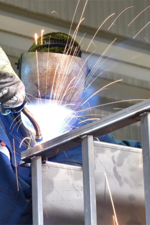 Portrait of factory worker in protective equipment holding thumb Portrait of factory worker in protective equipment holding thumbs up in production hall.