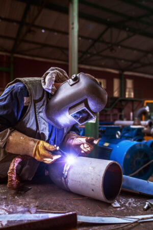 Industry male worker in protective uniform repairing metal pipe. Industry male worker in protective uniform repairing metal pipe.