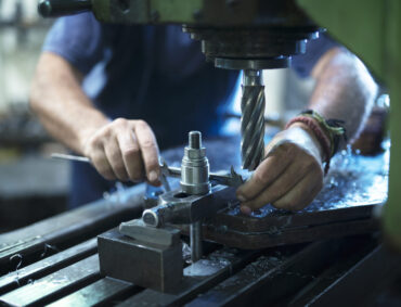 Worker operating industrial machine in metal workshop.
